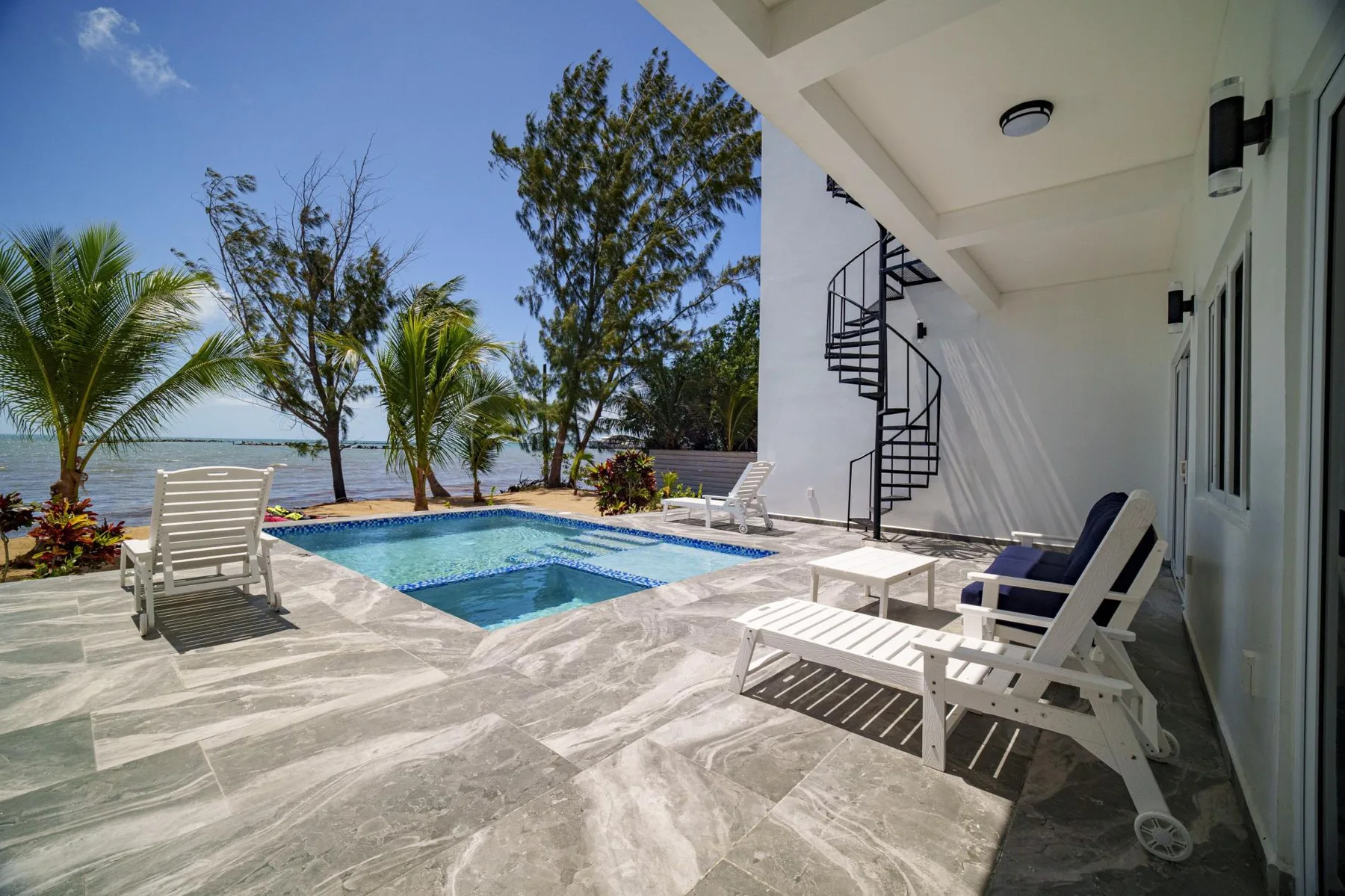 An outdoor poolside patio with lounge seating overlooks the water.