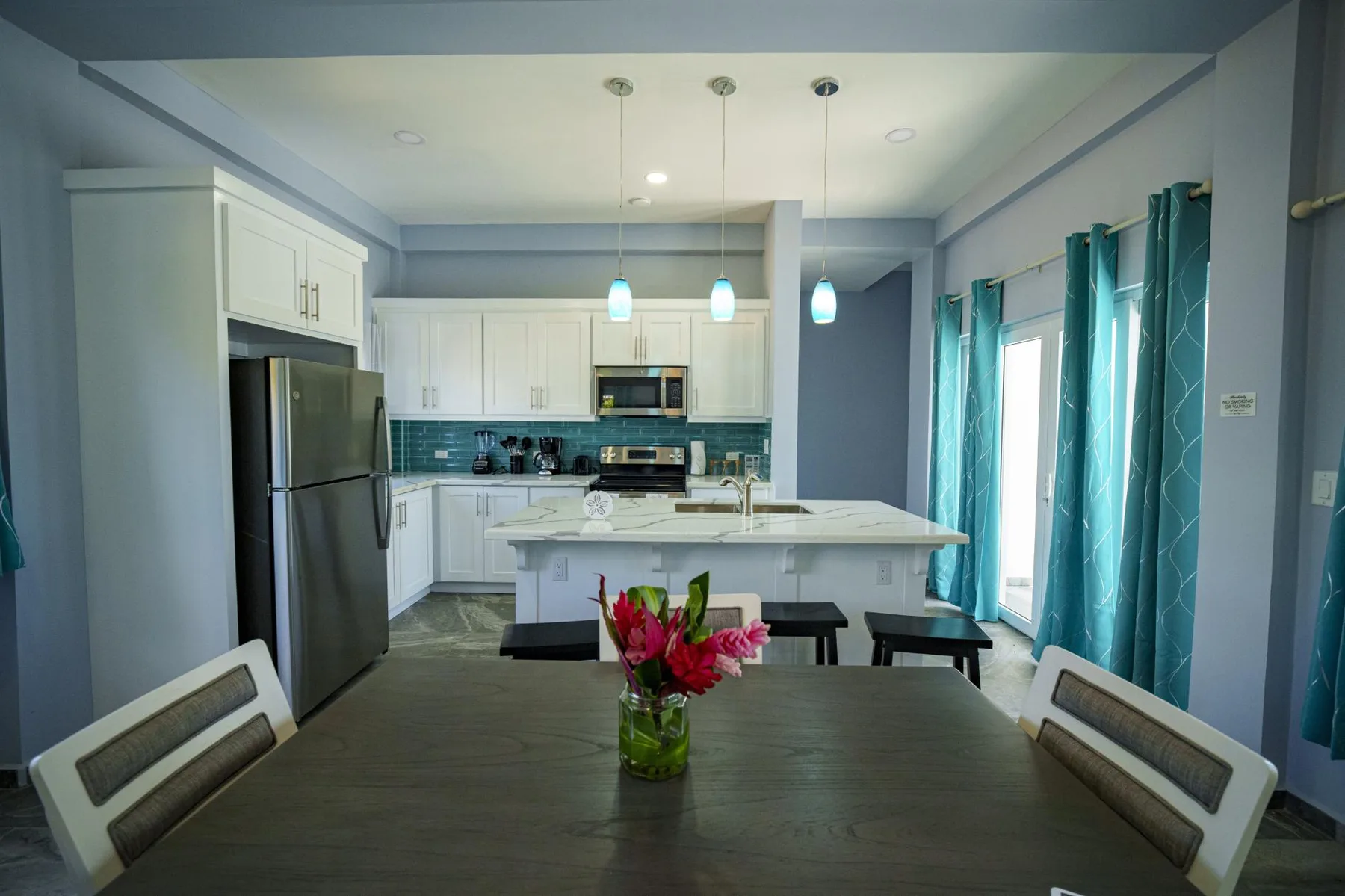 A bright kitchen and dining area with white cabinets, an island, and a dining table.