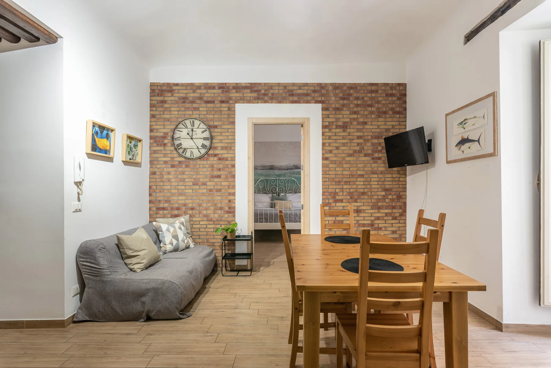 A living and dining area with a gray sofa beside a wooden table.