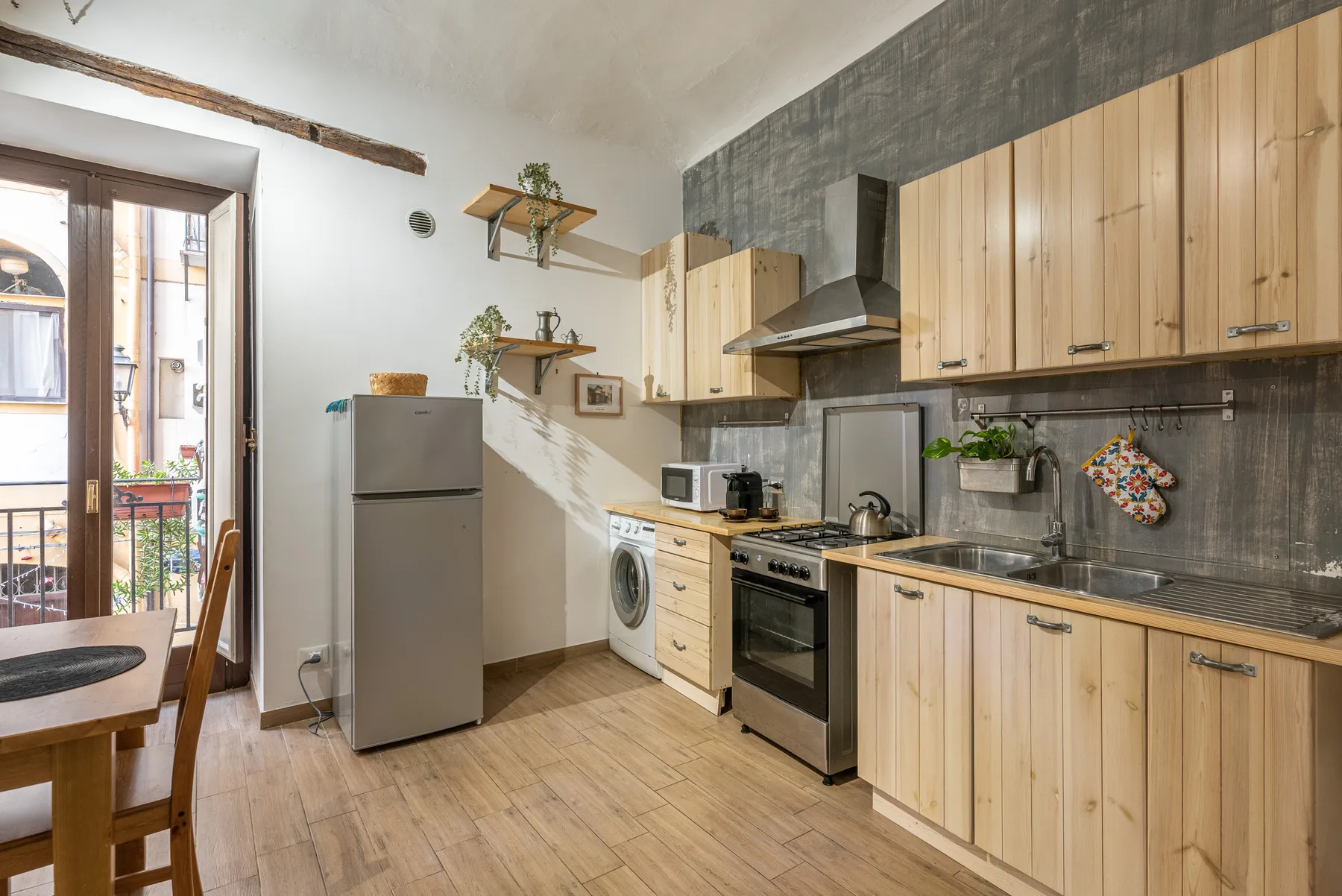 A kitchen with wooden cabinets, appliances, and a dining table by the window.