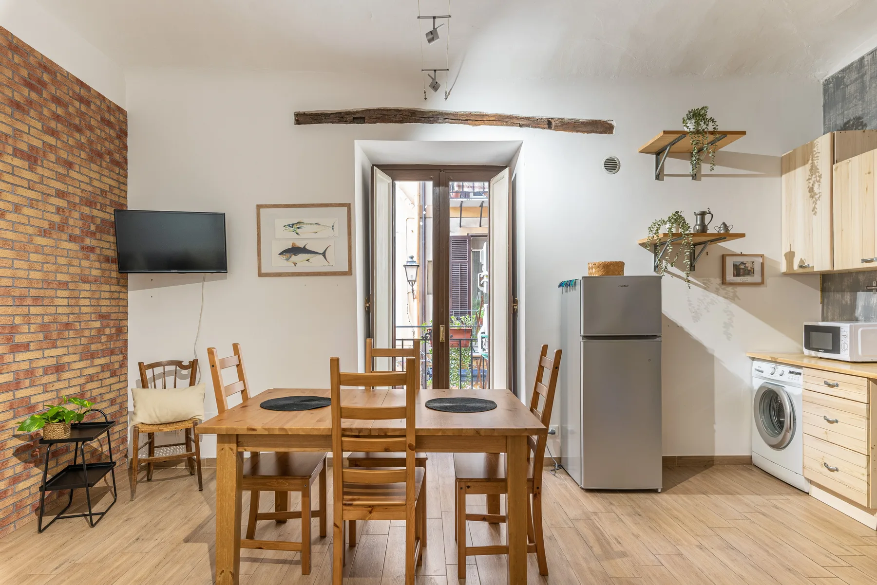 A dining area with a wooden table and chairs beside an open doorway.