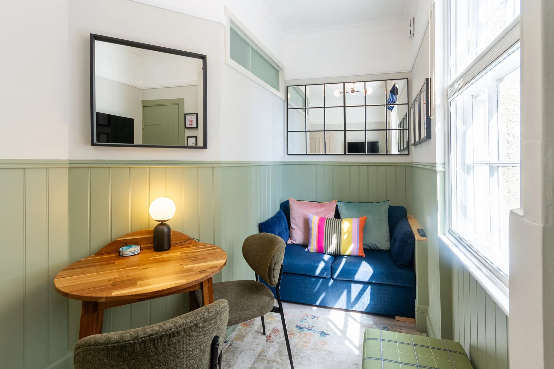 A bright sitting area with a blue sofa and large windows.