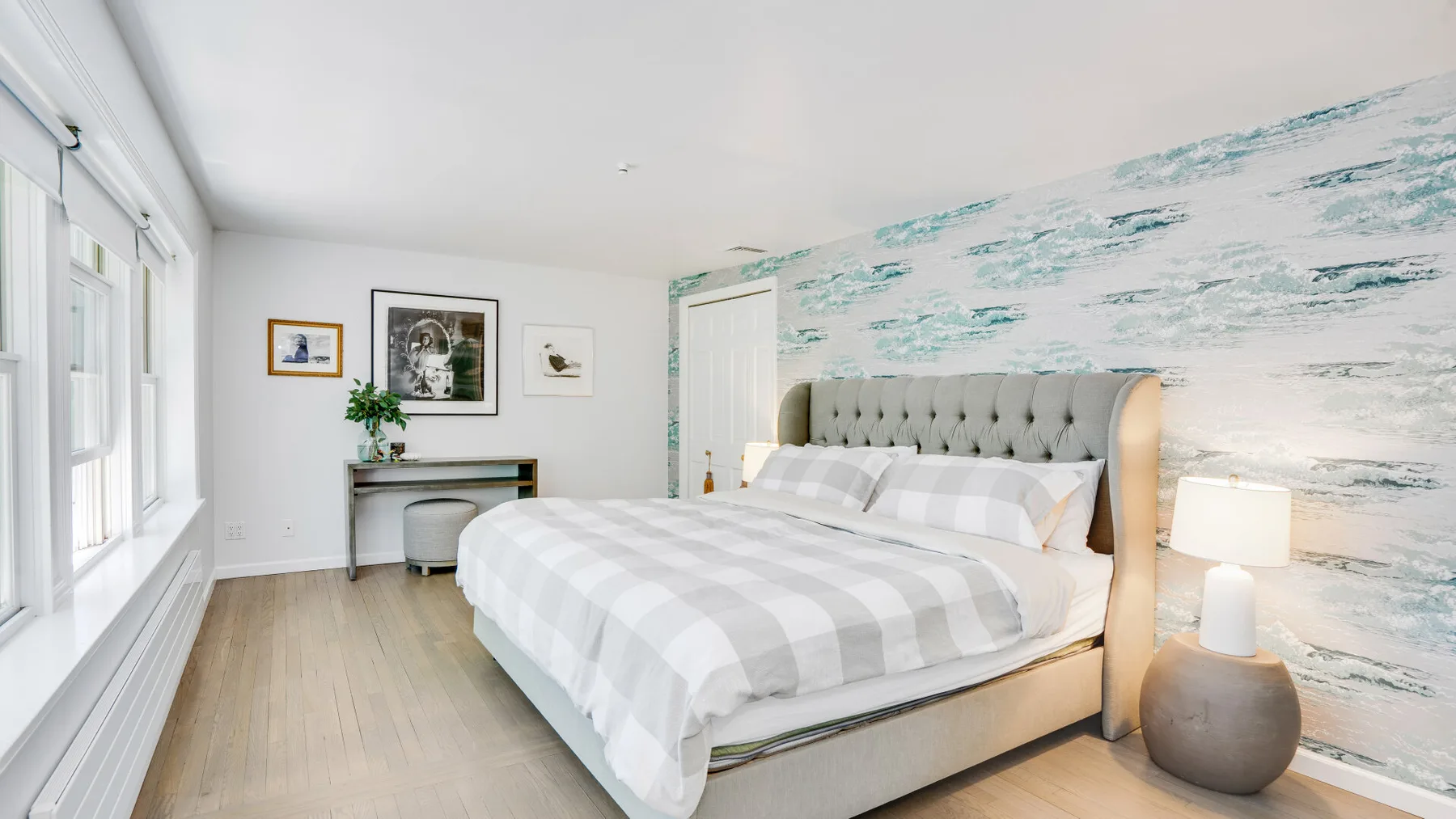 Un dormitorio luminoso con una cama grande y una pared estampada en azul y blanco.