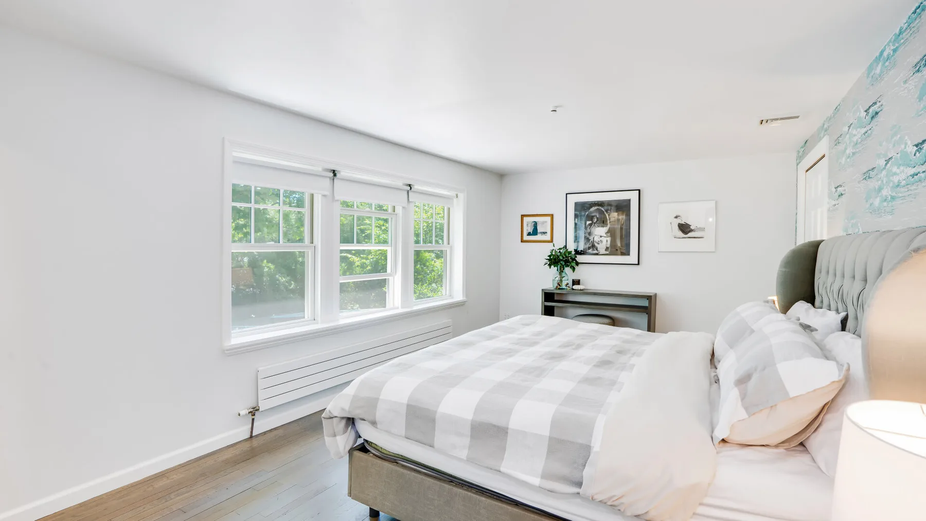 Un dormitorio luminoso con una cama junto a una fila de ventanas.