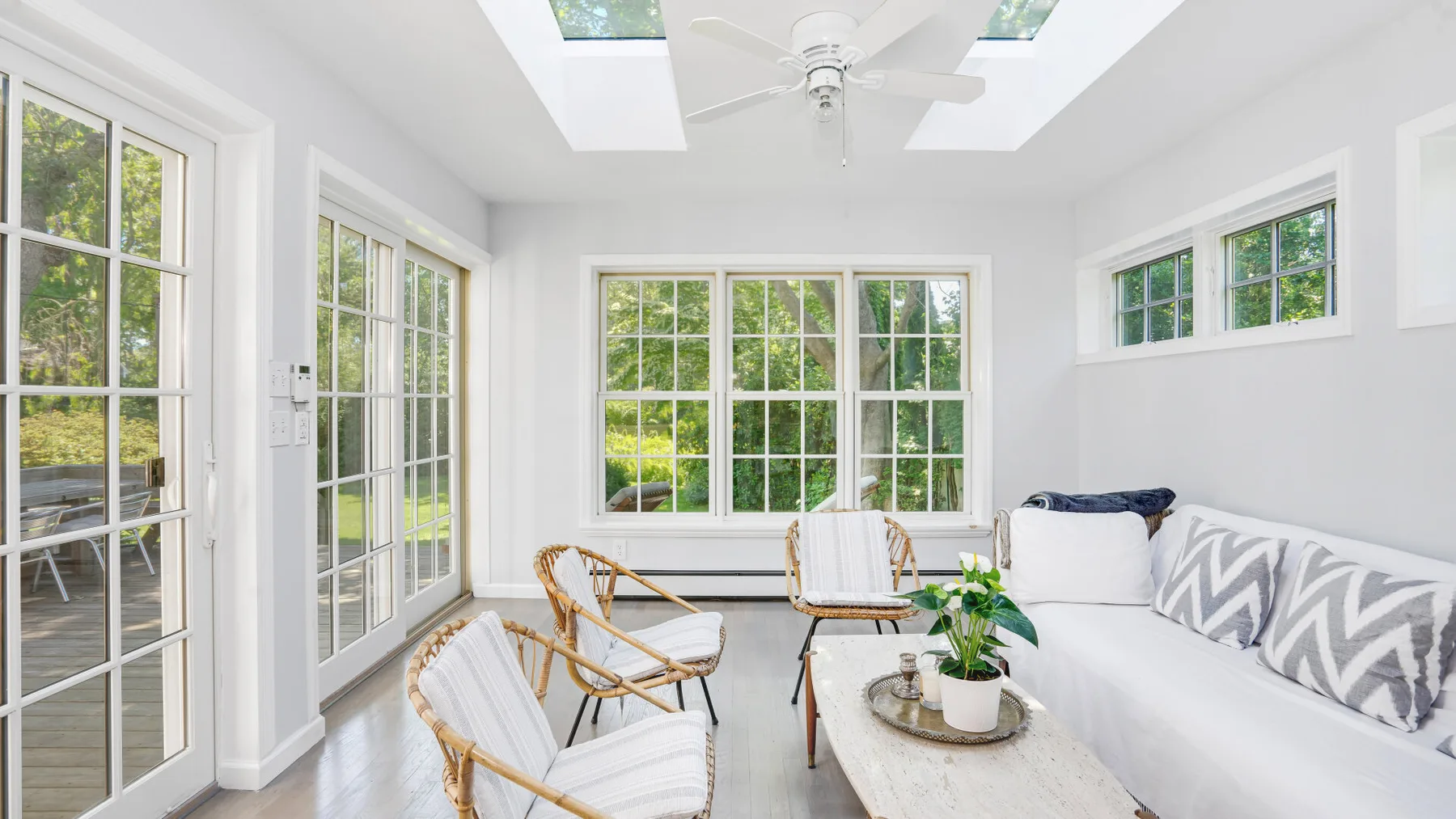 Un luminoso salón acristalado con grandes ventanas y una zona de asientos blanca.