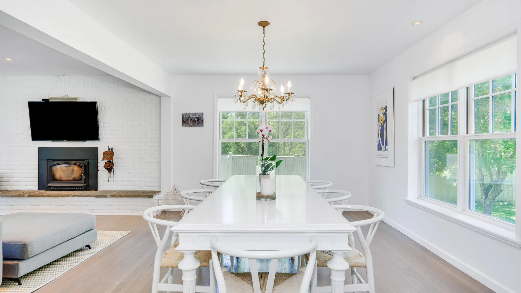 Un comedor luminoso con una mesa blanca larga bajo una lámpara de araña.