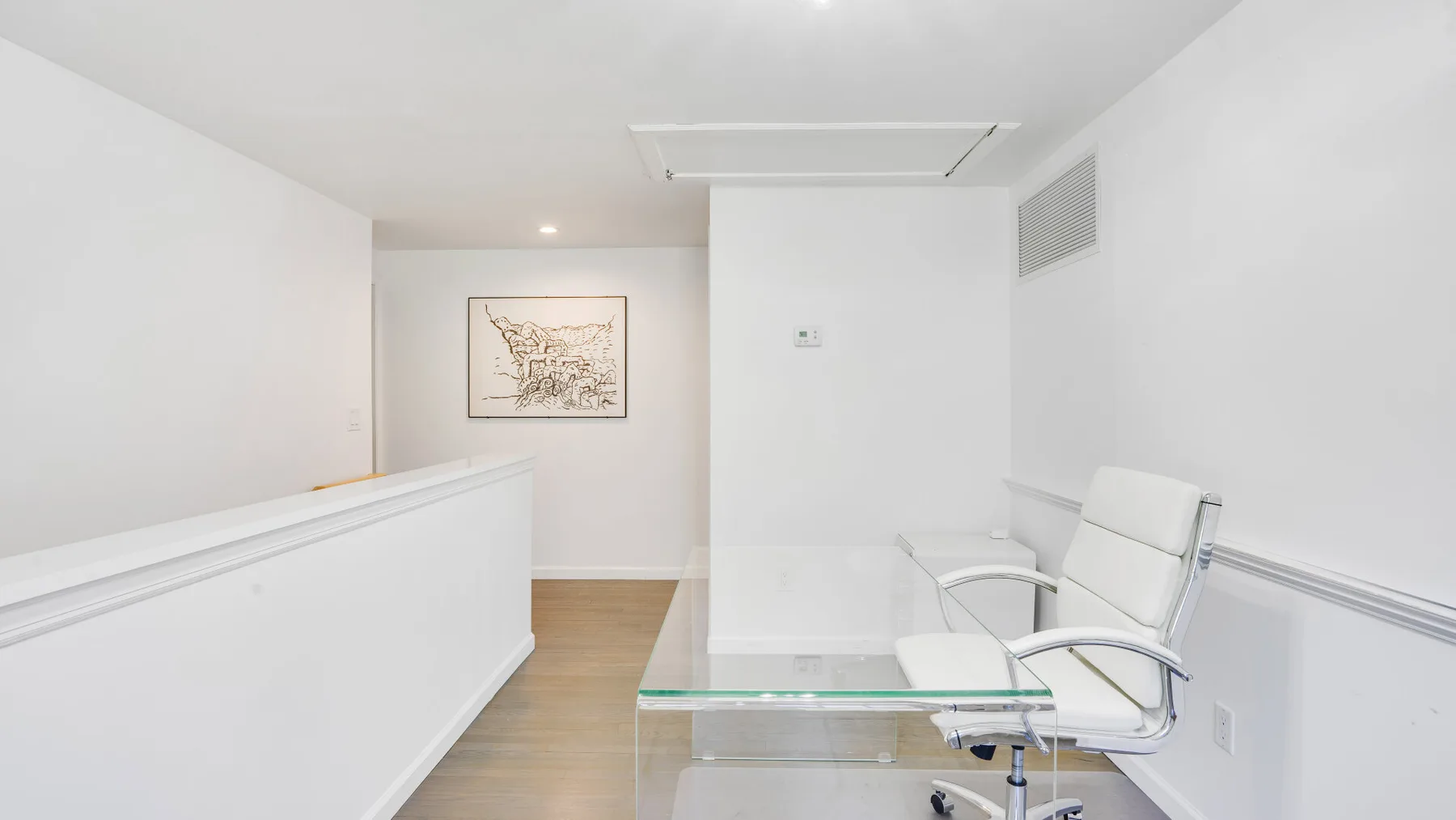 Una luminosa zona de recepción con mostrador blanco, mesa de vidrio y asientos.