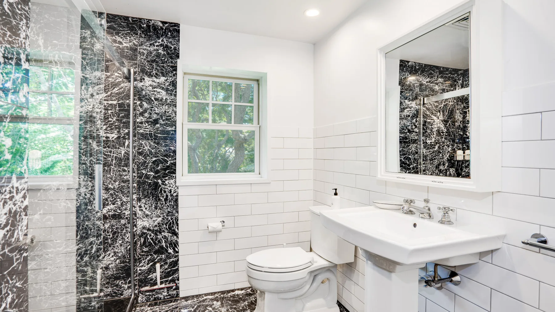 Un baño luminoso con lavabo blanco, inodoro y zona de ducha con azulejos.