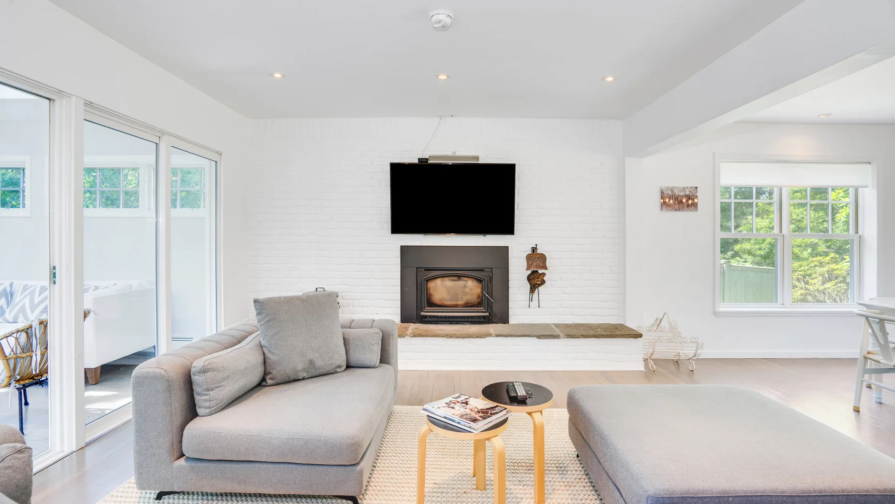 Una sala luminosa tiene una zona de estar, una chimenea y un televisor.