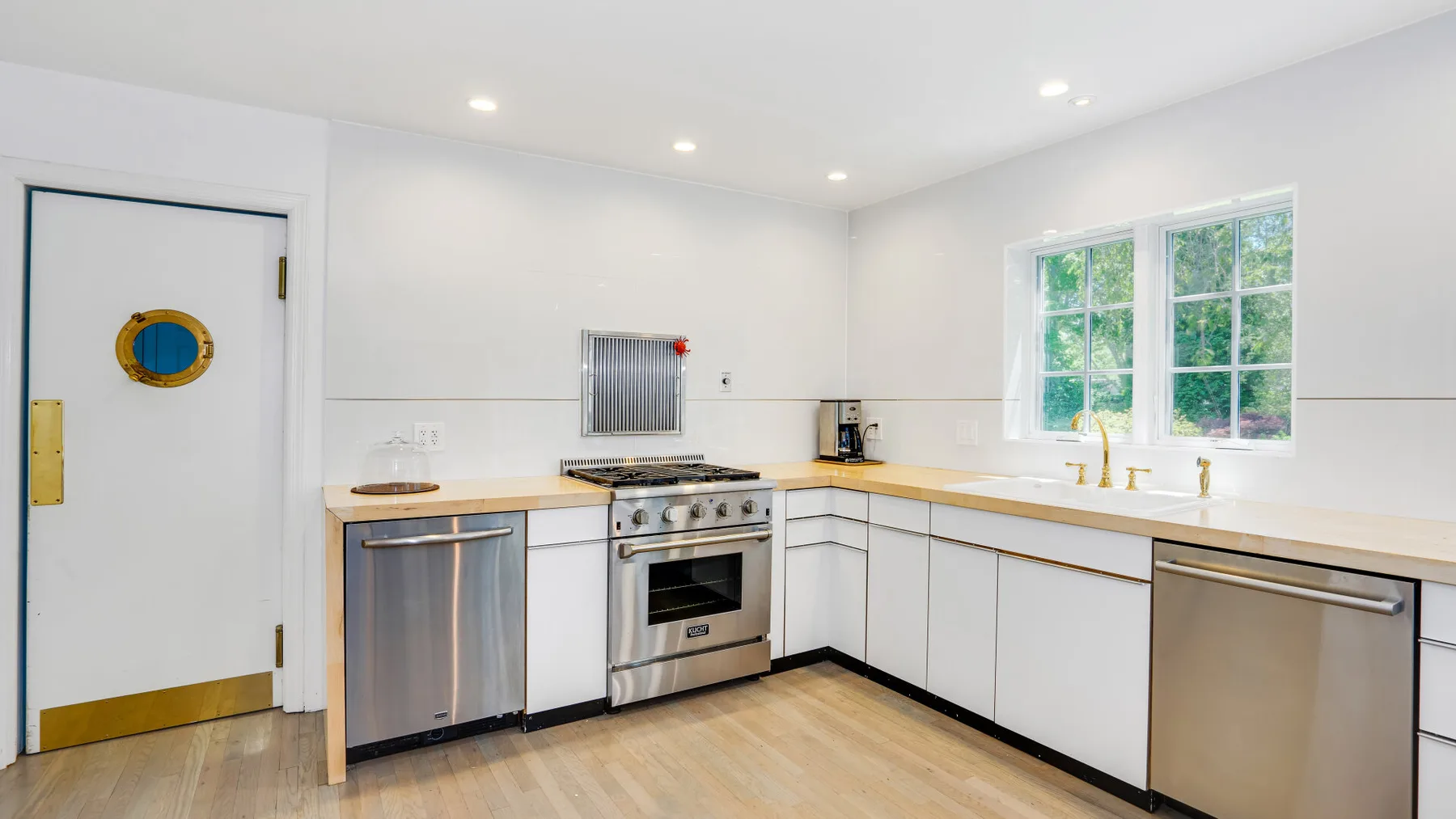 Una cocina luminosa con gabinetes blancos, electrodomésticos de acero inoxidable y una ventana.