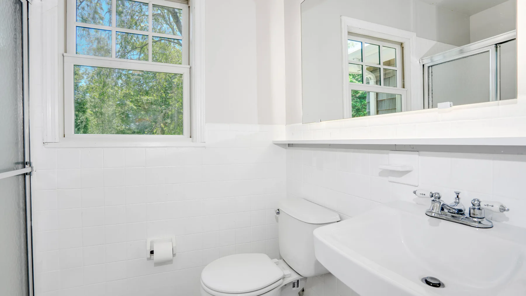 Un baño luminoso con lavabo, inodoro y ventana.