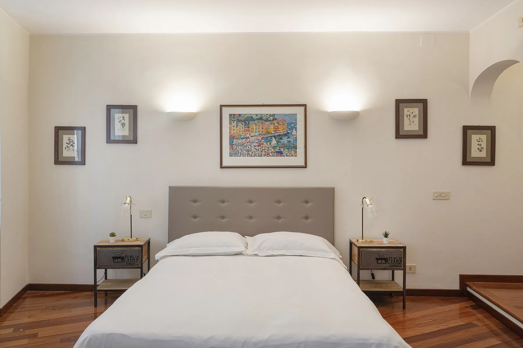Un dormitorio con una cama bien hecha, mesas de noche a juego y cuadros enmarcados.