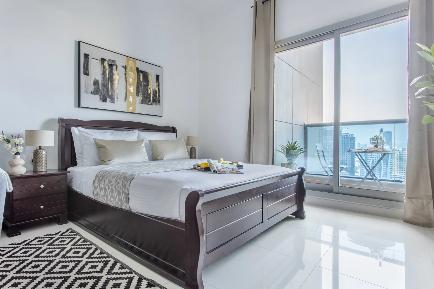 A bright bedroom with a neatly made bed beside a large window.