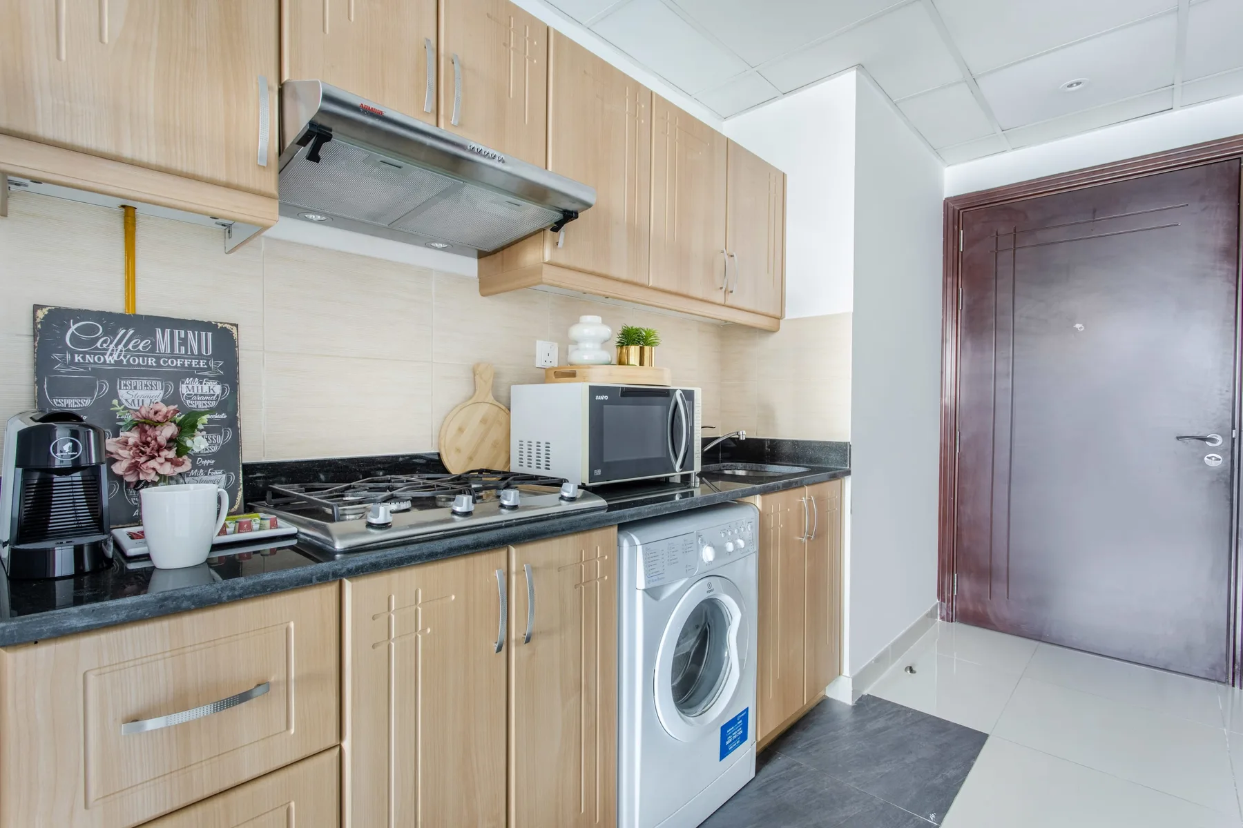 A compact kitchen with wooden cabinets, a countertop, and a washing machine.