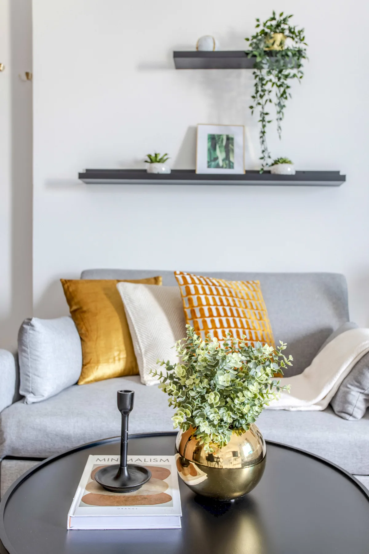 Una sala de estar con un sofá gris, cojines de colores y una mesa de centro redonda.