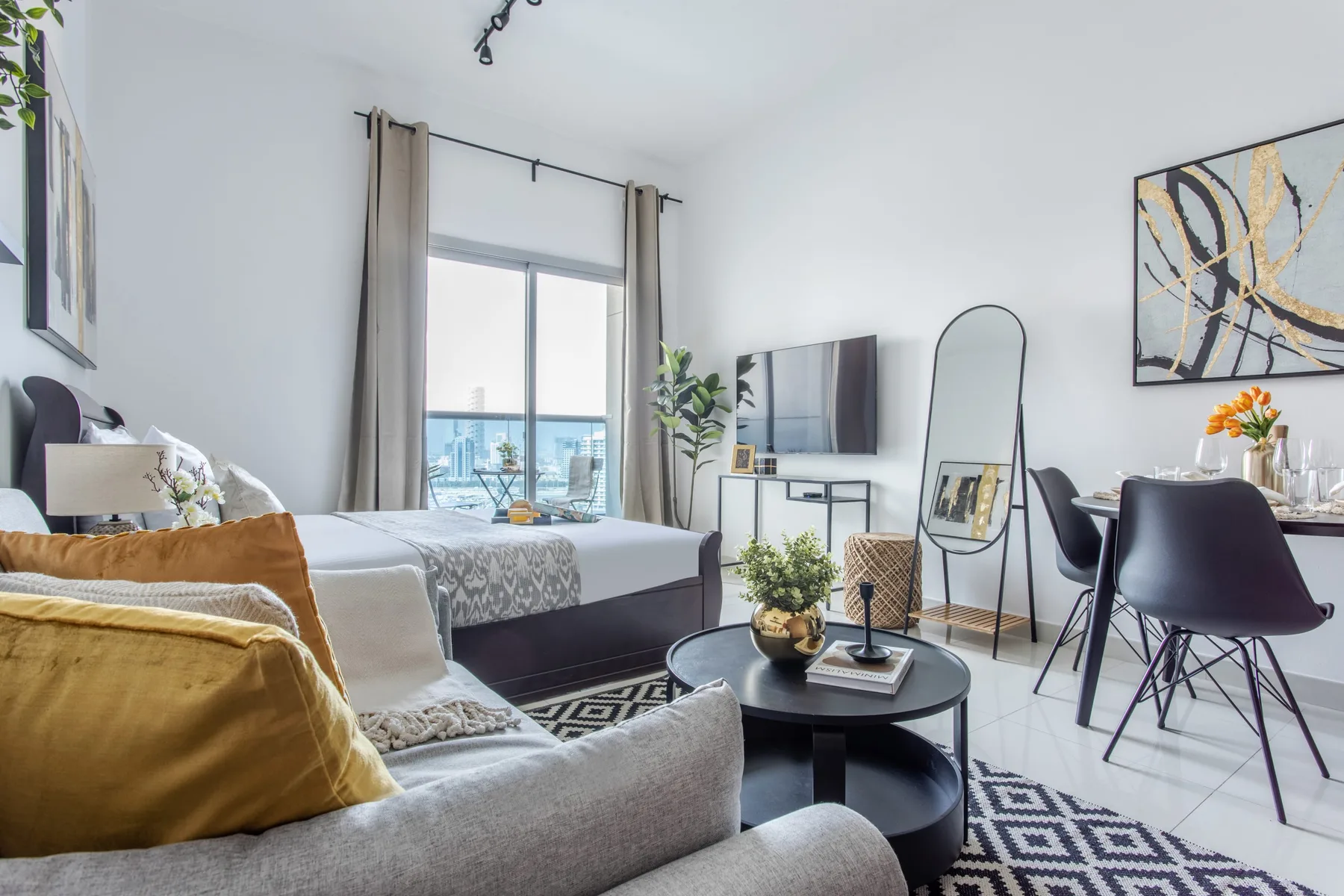 A bright living area combines a seating space, dining table, and large window.