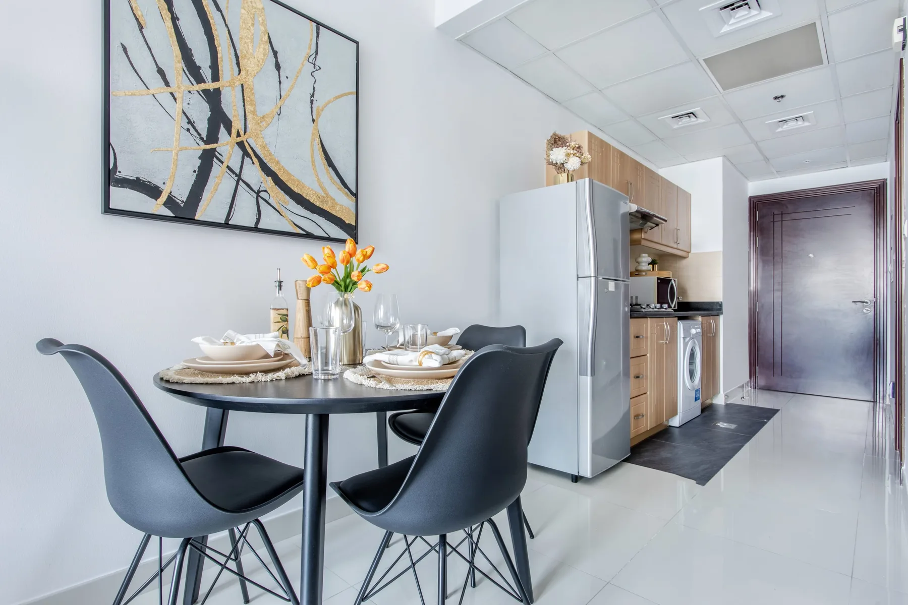 Comedor con una mesa redonda y sillas junto a una cocina compacta.