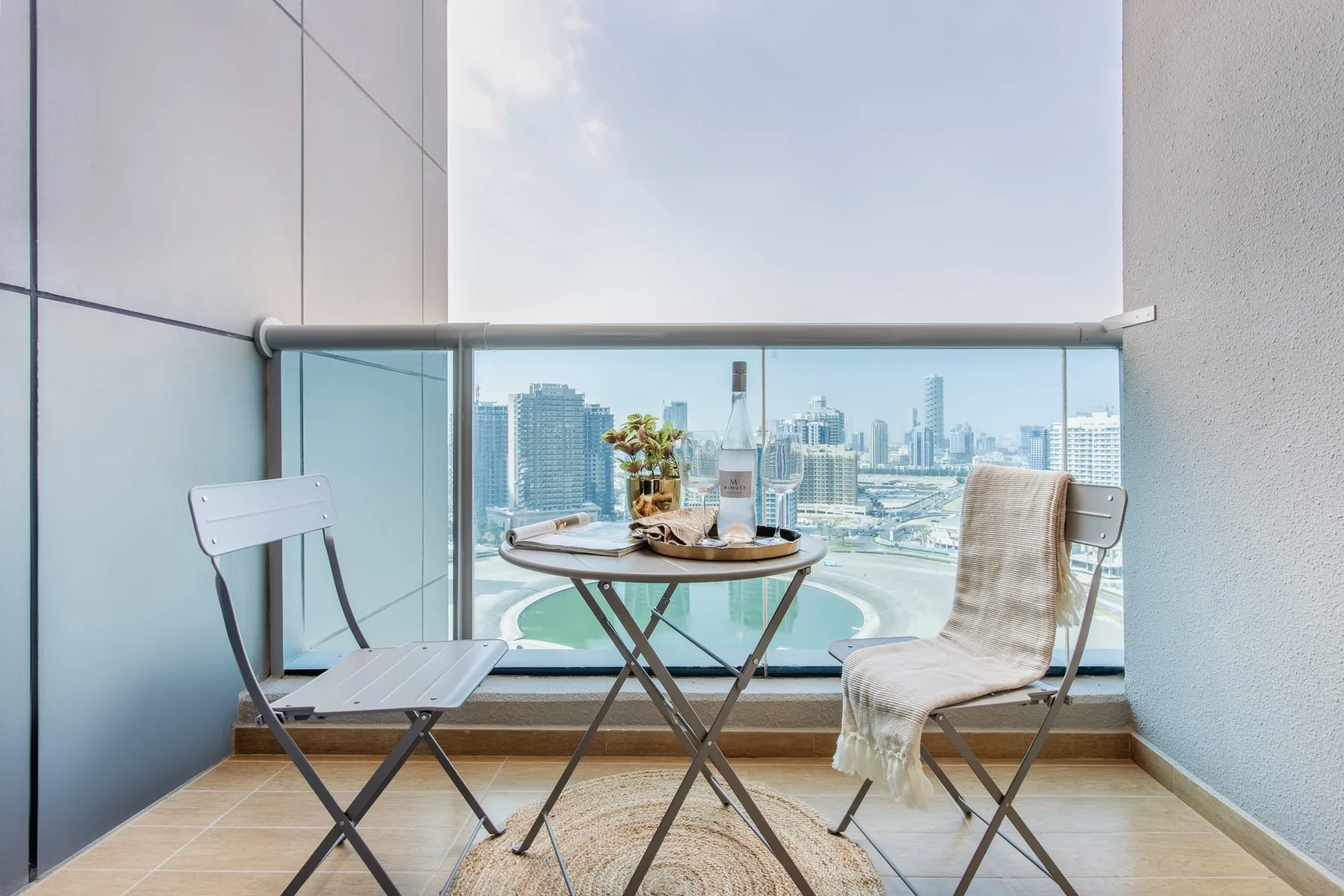 A balcony seating area overlooks the city skyline through a glass railing.