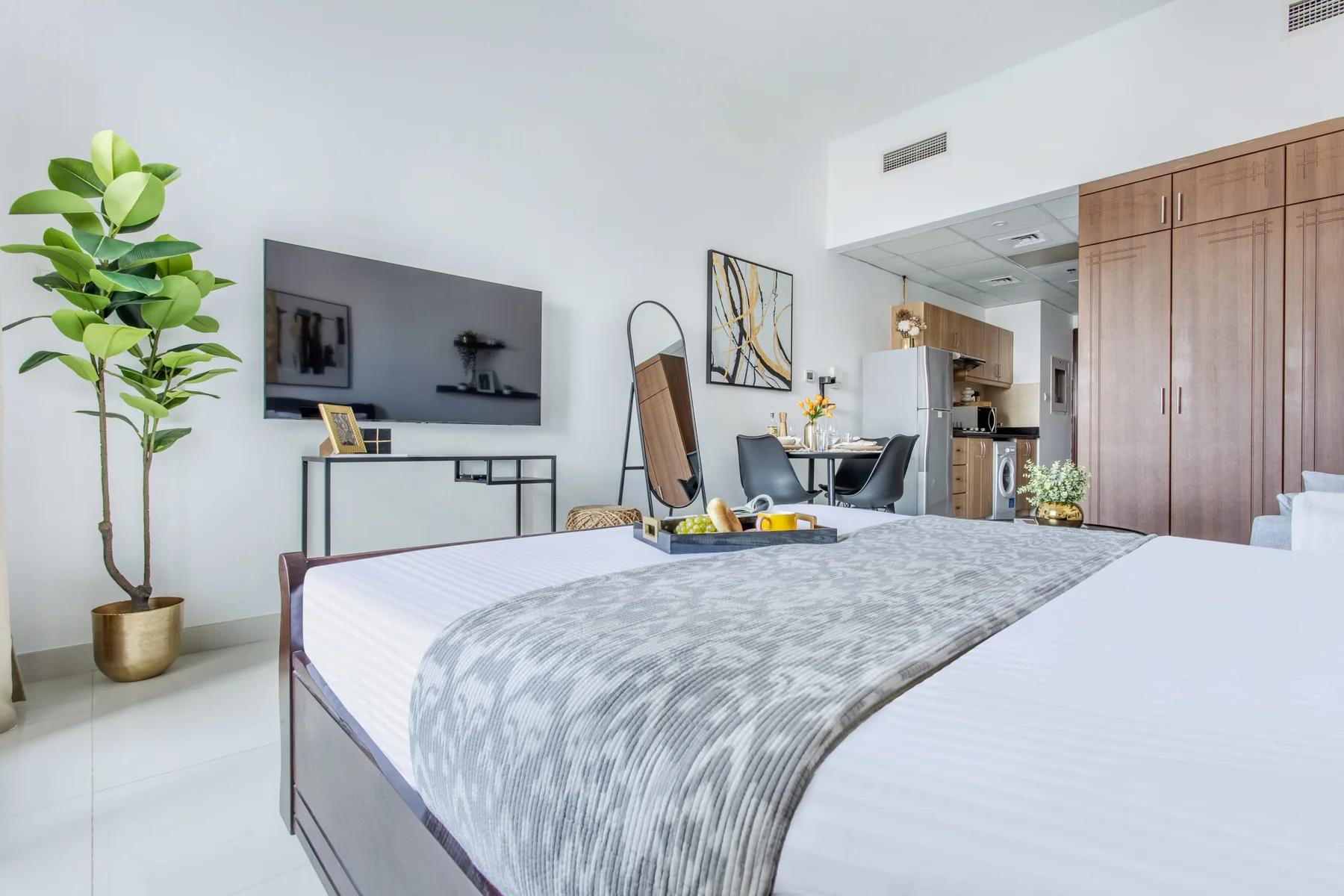 A bedroom with a large bed, a television, and a dining area.