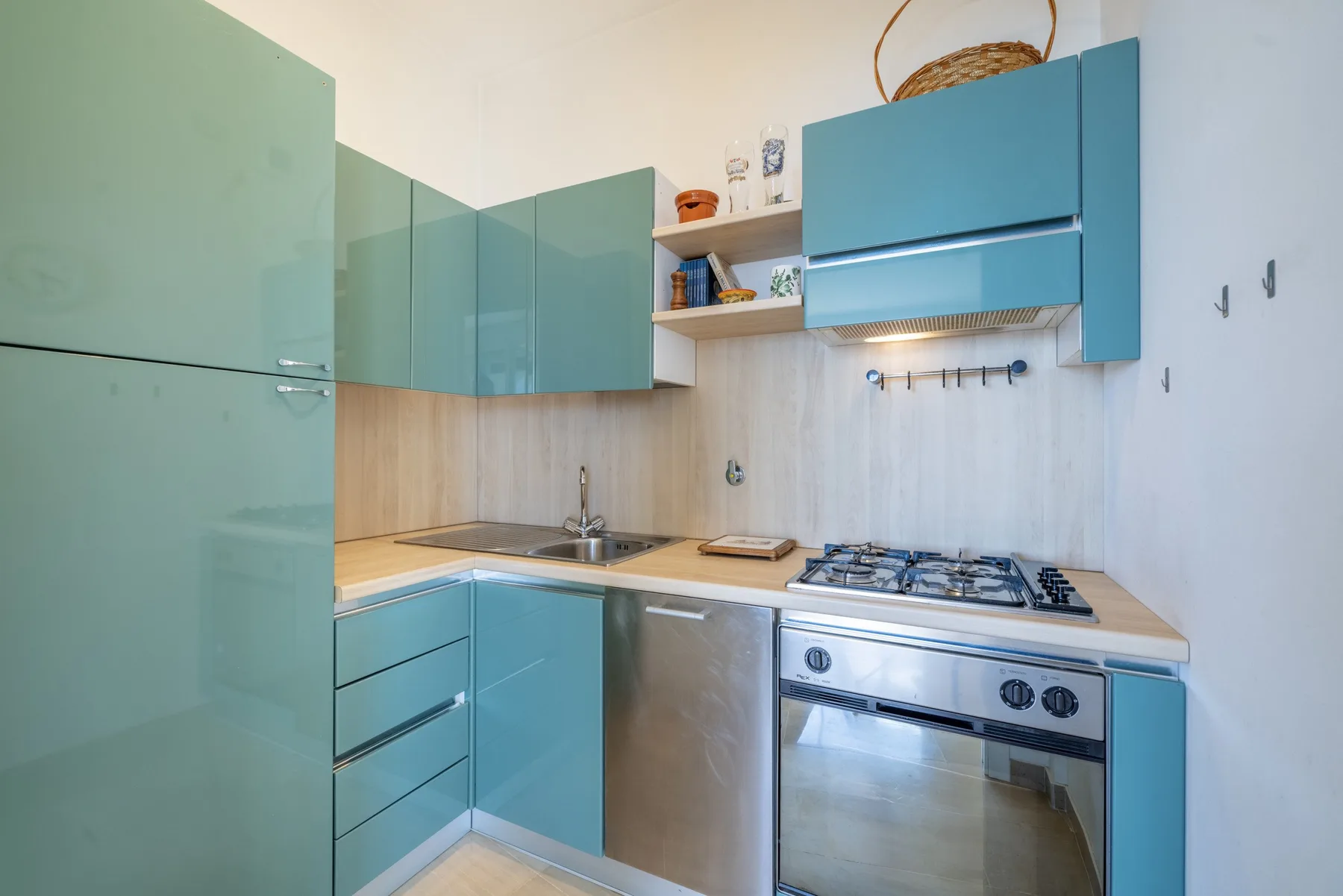 Una cocina compacta con gabinetes color turquesa, encimera y horno integrado.