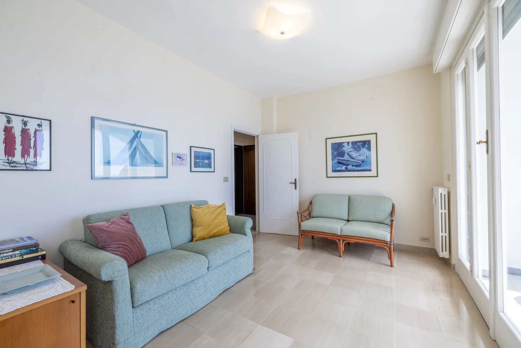 Una sala luminosa con asientos, cuadros enmarcados y grandes ventanas.