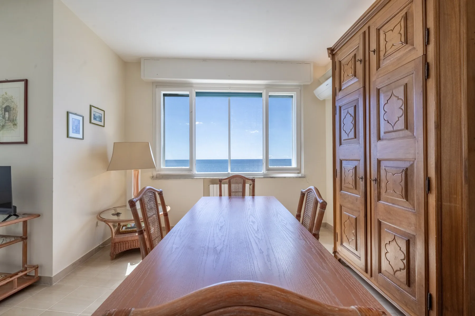 Un comedor con una larga mesa de madera y una ventana con vistas al mar.