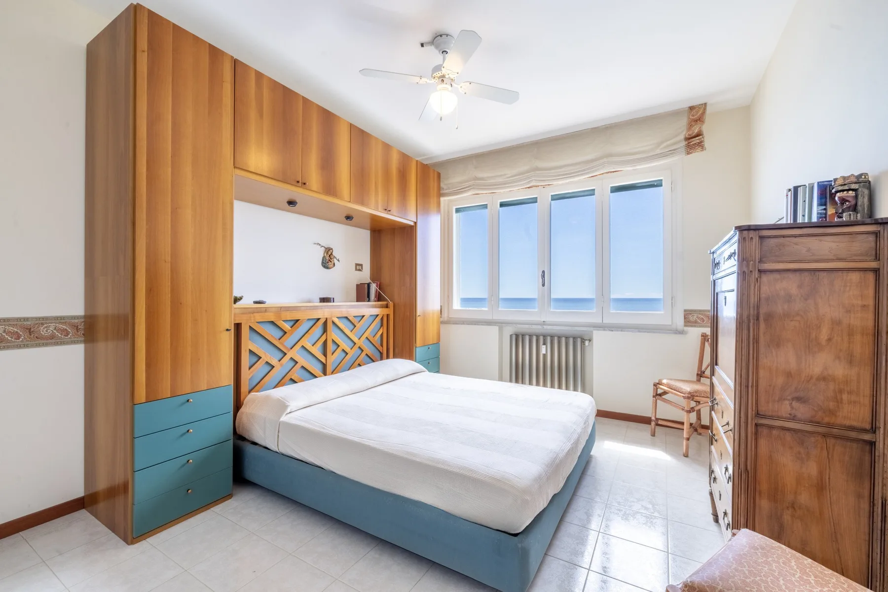 Un dormitorio con una cama, armarios de madera y una ventana amplia.