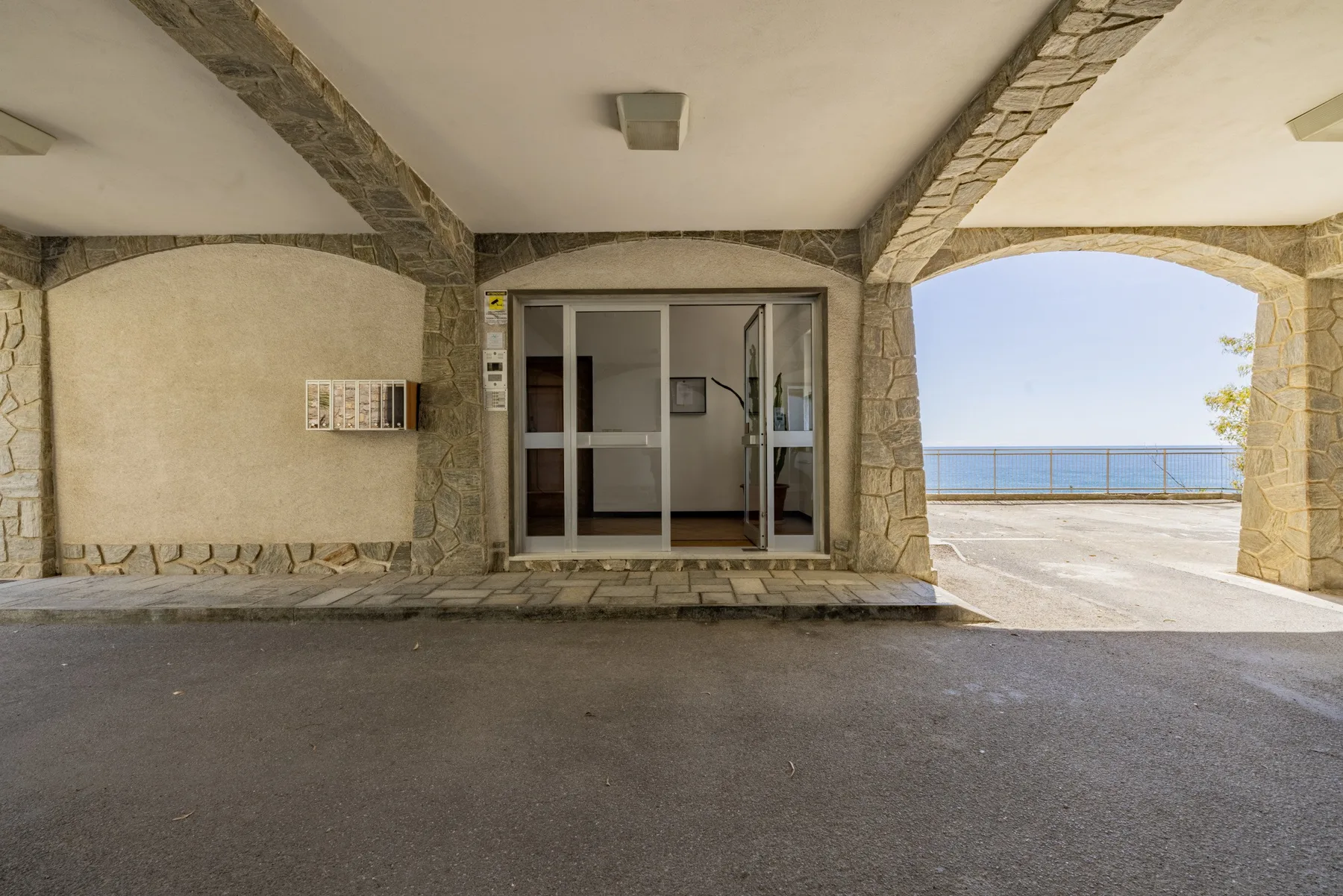 Un pasillo cubierto de piedra da a una terraza con vistas al mar.