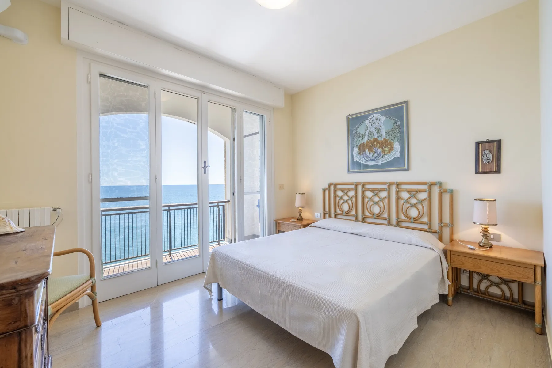 Un dormitorio con una cama junto a puertas de vidrio que dan al mar.