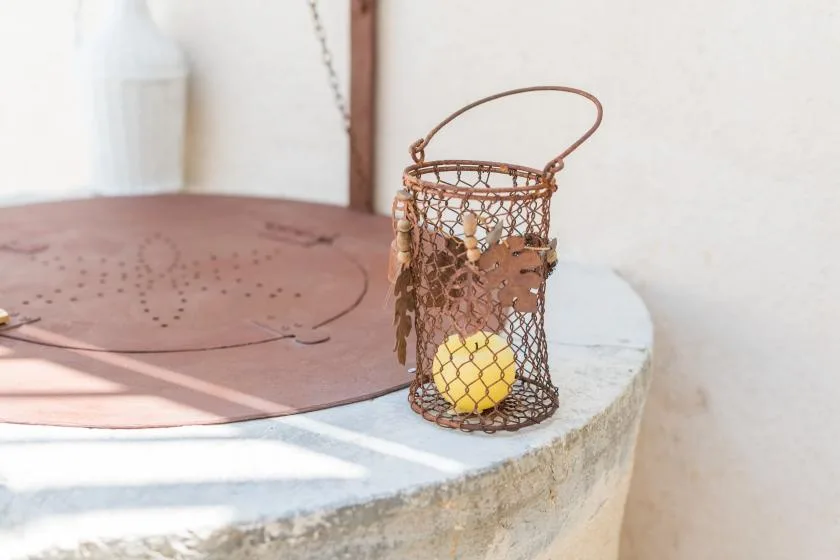 A small yellow ball rests in a wire basket on a round stone surface.