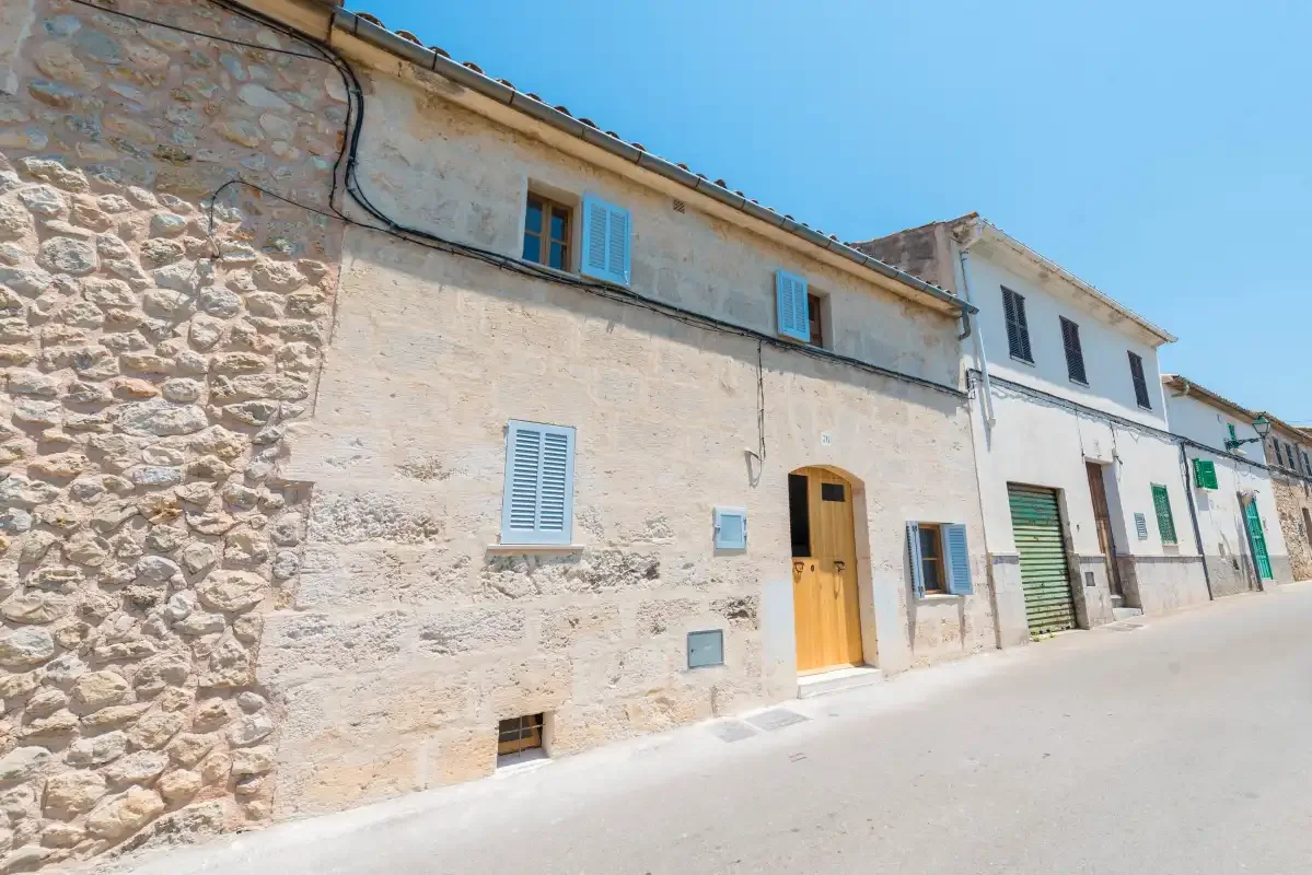 A row of pale stone buildings lines a sunlit street.