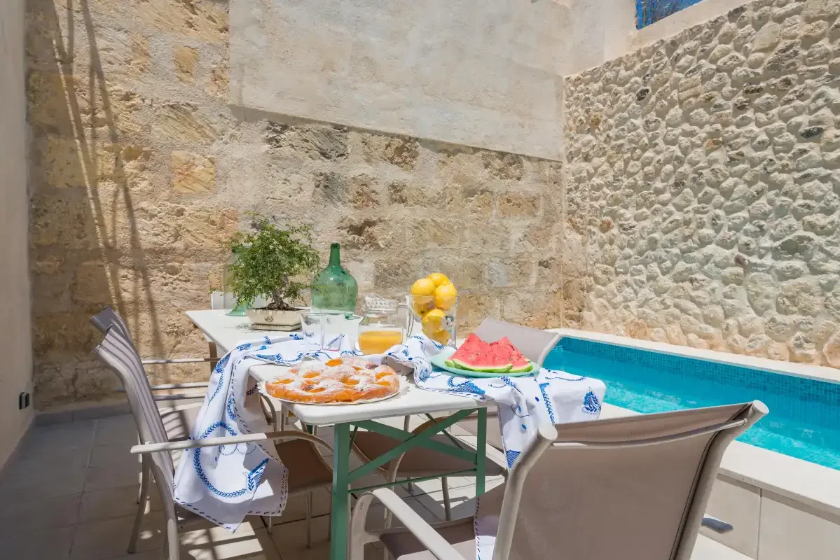 A poolside dining area with a table set beside a small swimming pool.