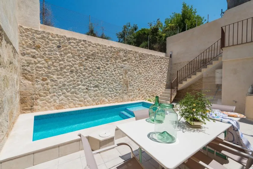 An outdoor poolside patio with a white table and seating.