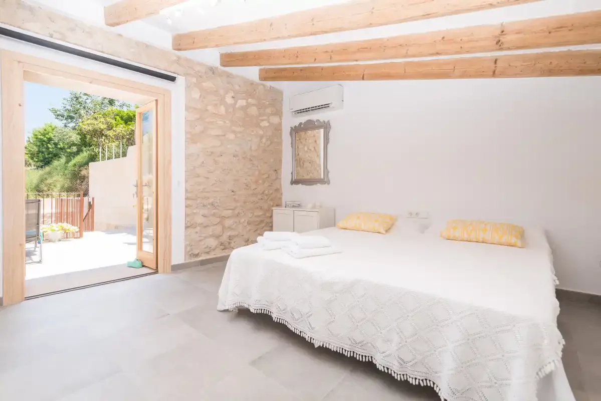 A bright bedroom with a bed beside an open doorway to the outdoors.