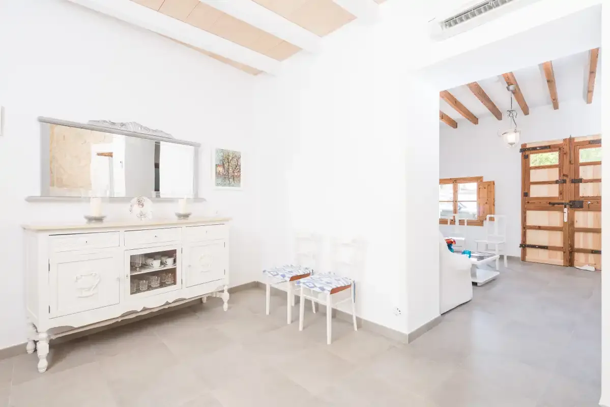 A bright living area with white seating and a wooden-beamed ceiling.