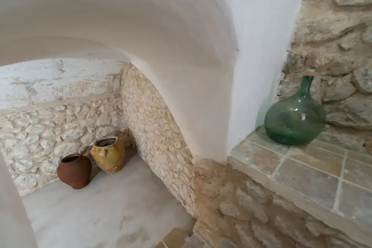 A stone alcove displays pottery beside a tiled ledge.