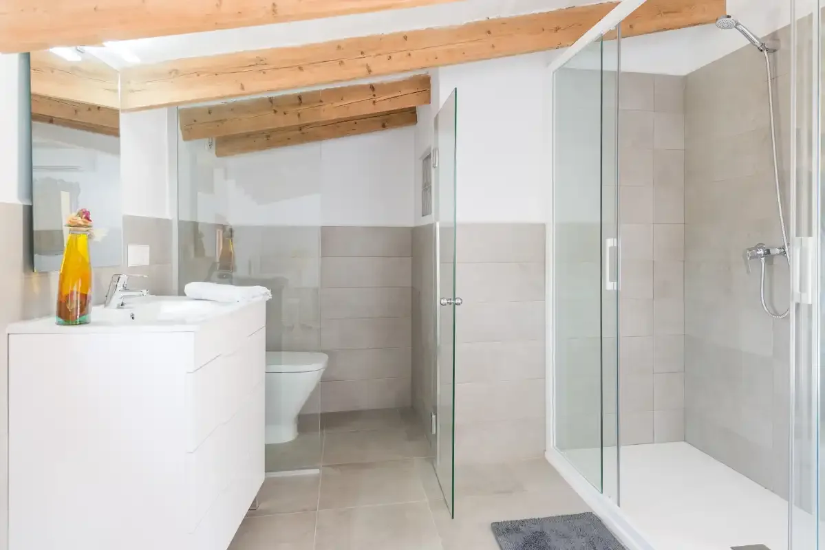 A tiled bathroom with a white vanity and glass shower.