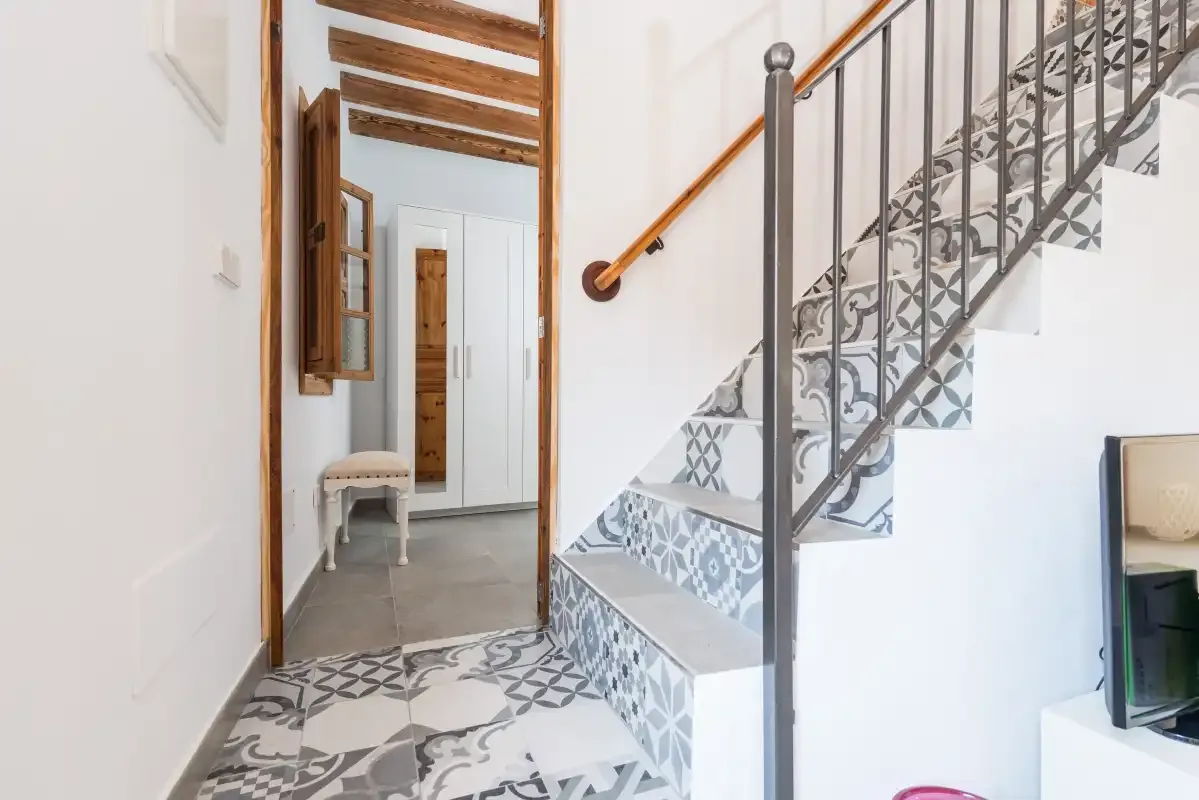 An interior hallway with patterned tile flooring and a staircase.