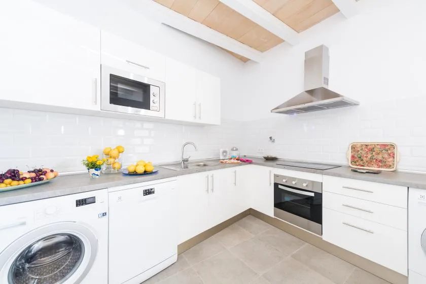 A bright modern kitchen with white cabinets, a countertop, and built-in appliances.