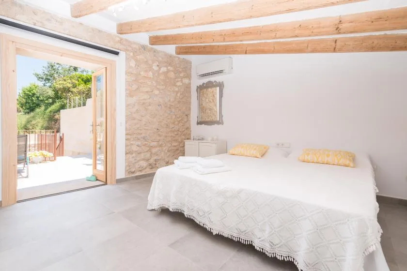 A bright bedroom with a double bed and an open doorway to a patio.