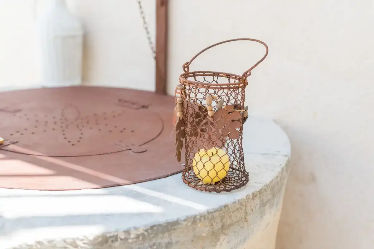 A rustic metal lantern sits on a round stone surface.