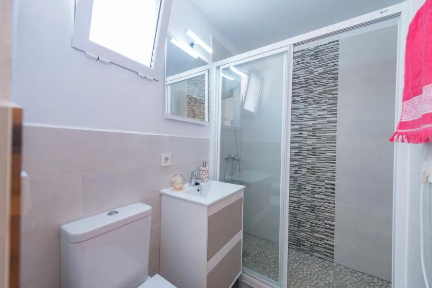 A bathroom with a vanity, toilet, and glass shower.
