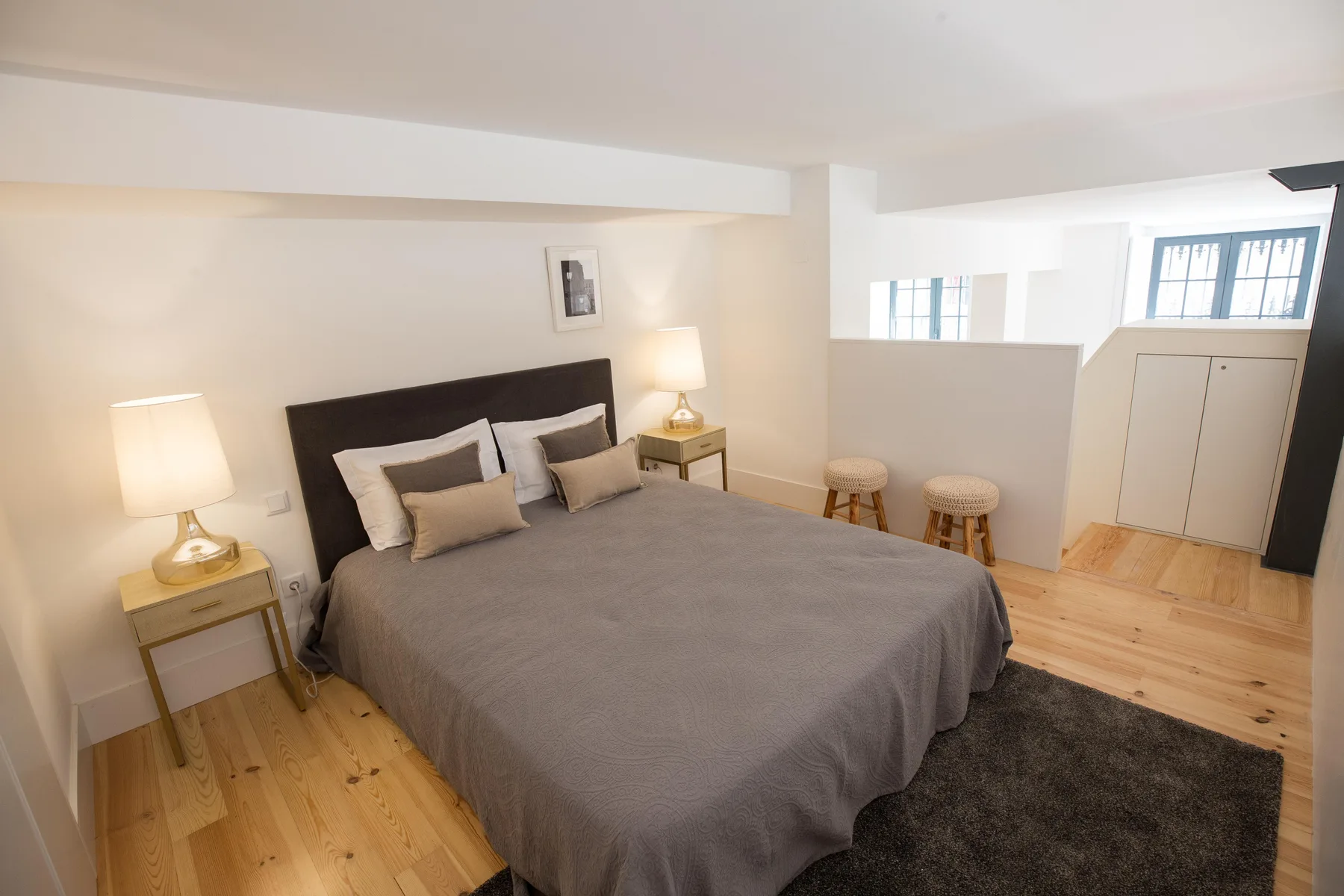 Un dormitorio con una cama, mesitas de noche y una pequeña zona para sentarse.