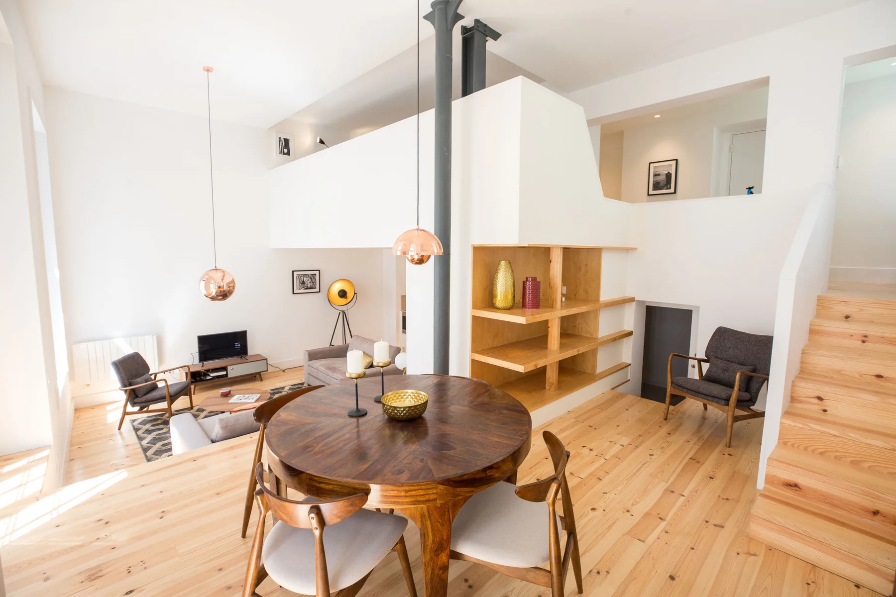 Una luminosa sala de estar y comedor de planta abierta con suelo de madera y una mesa redonda.