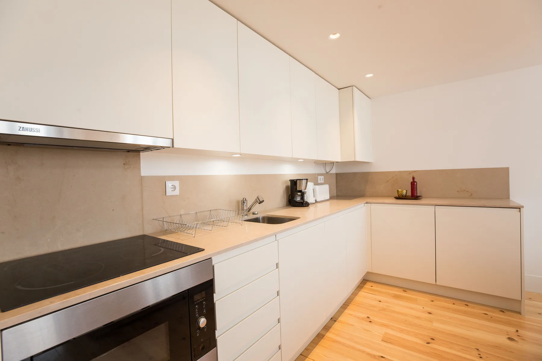 Una cocina moderna con armarios blancos, una placa de cocción y un fregadero.