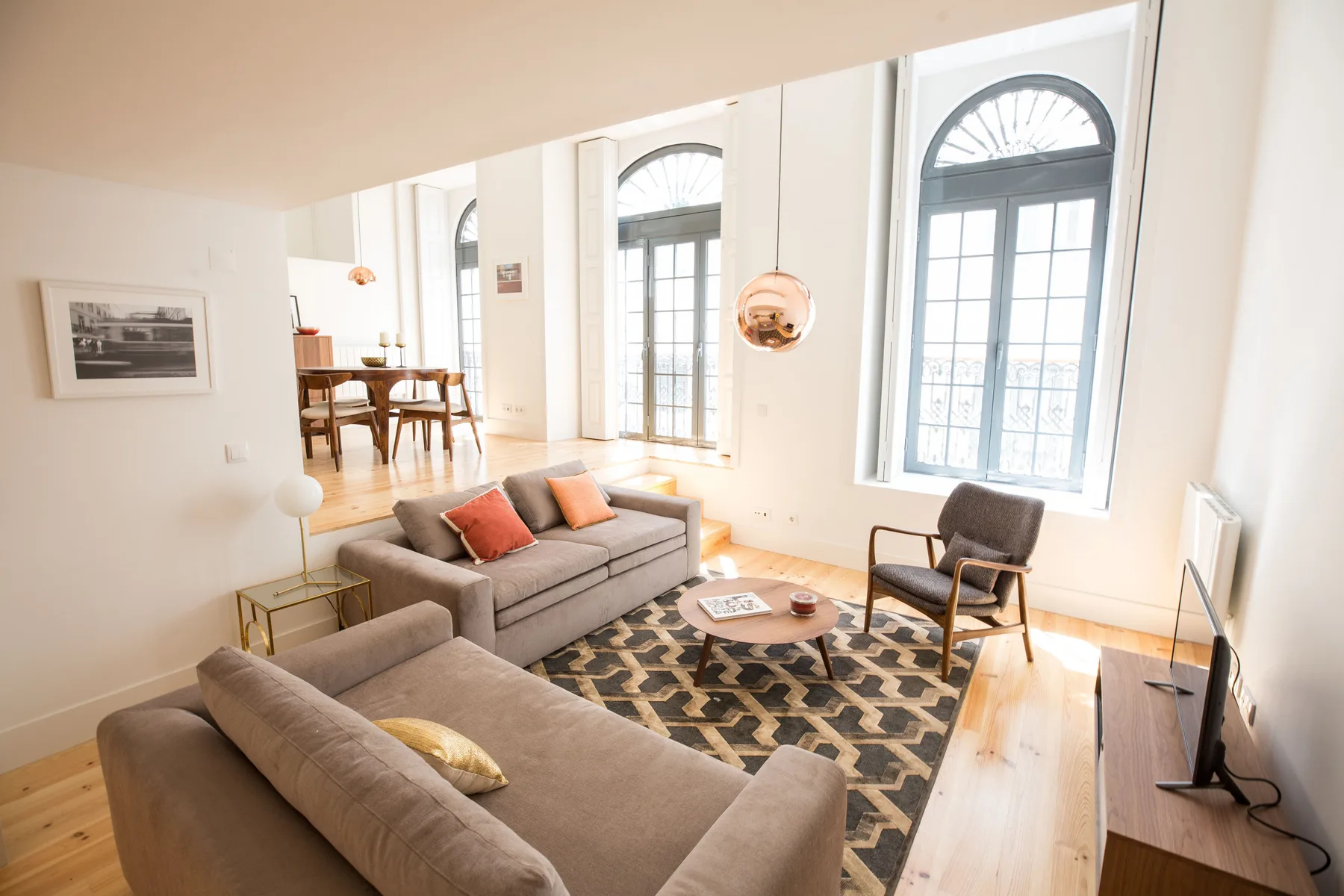 Una sala luminosa con asientos, una alfombra estampada y ventanas altas con arco.