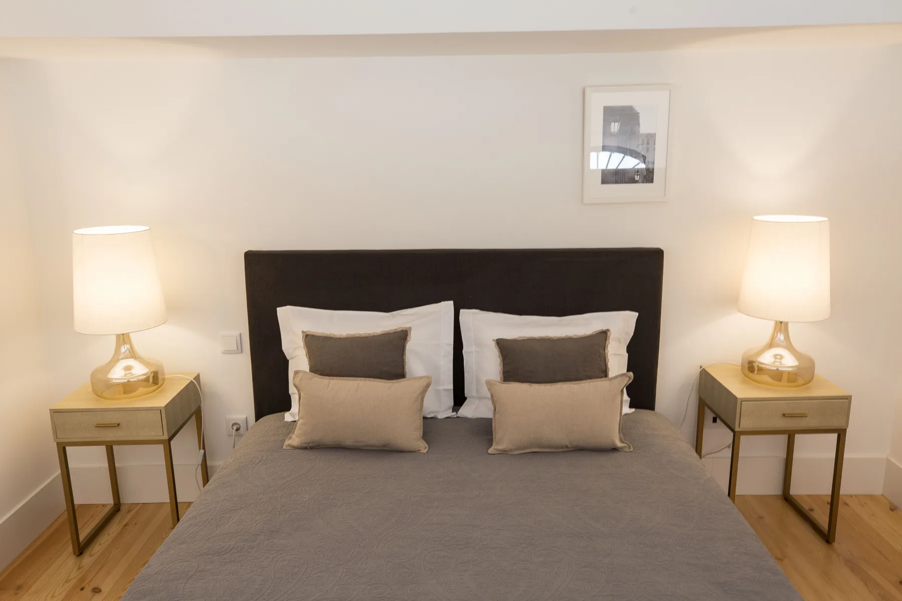 Un dormitorio con una cama bien hecha y lámparas a ambos lados.