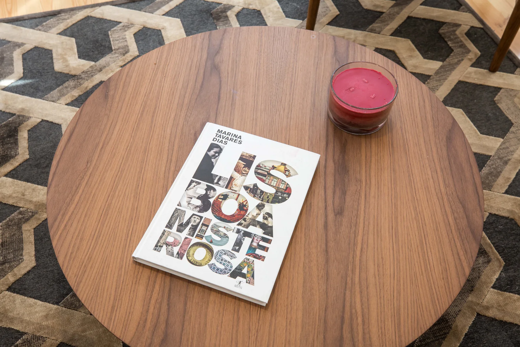 Una mesa redonda de madera tiene un libro y una pequeña vela roja.