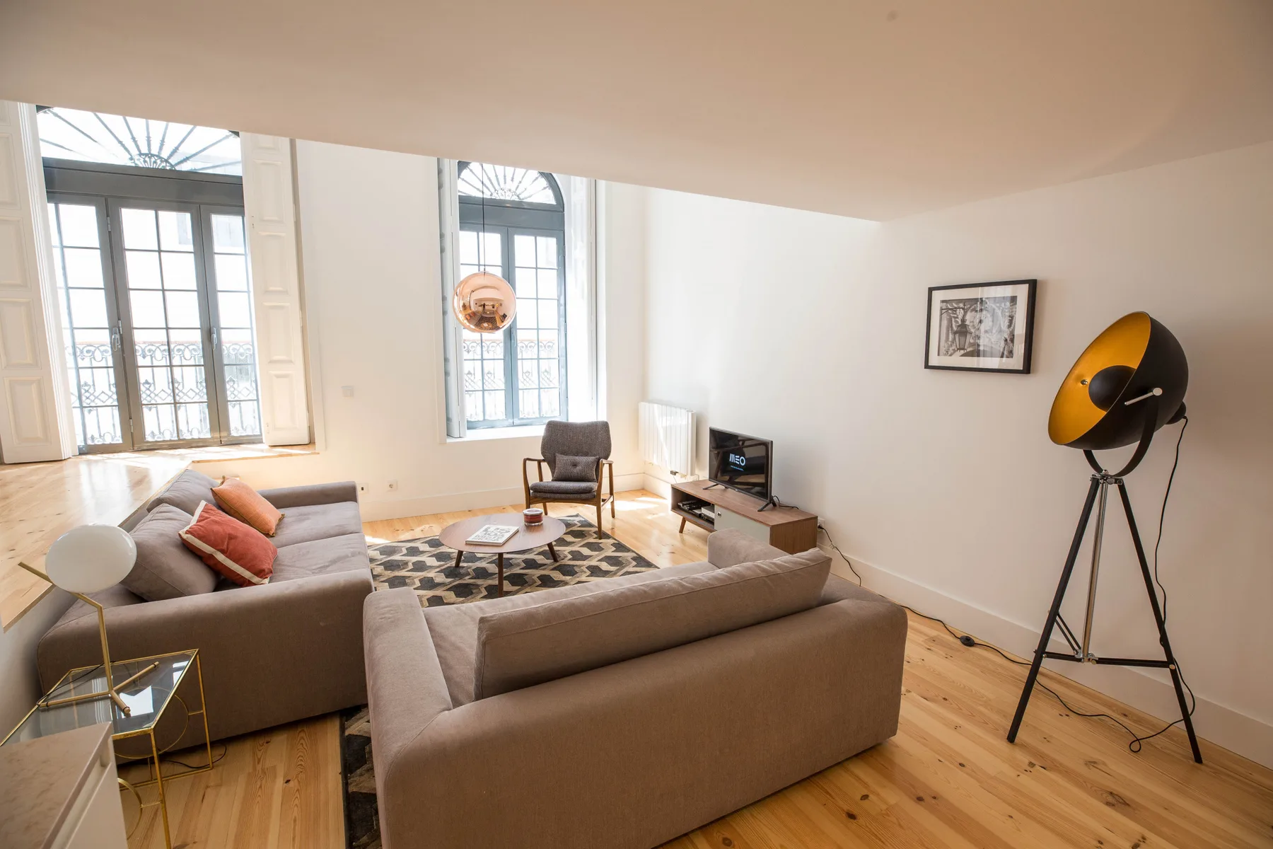 Una sala luminosa con asientos alrededor de una mesa baja y grandes ventanas.