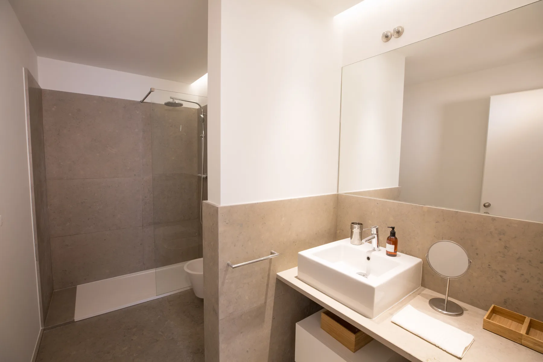 Un baño con lavabo, espejo grande y ducha.
